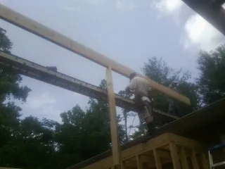 Carpenter setting a ridge beam over a new addition frame — Ice Dam Removal by Roofing Brothers in Humeston