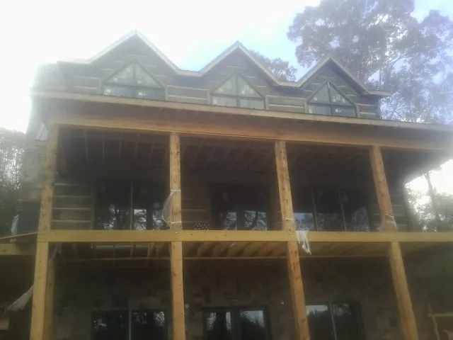 Dormers and porch framing on a large log home under construction — Roof Coating work by our crew in Humeston