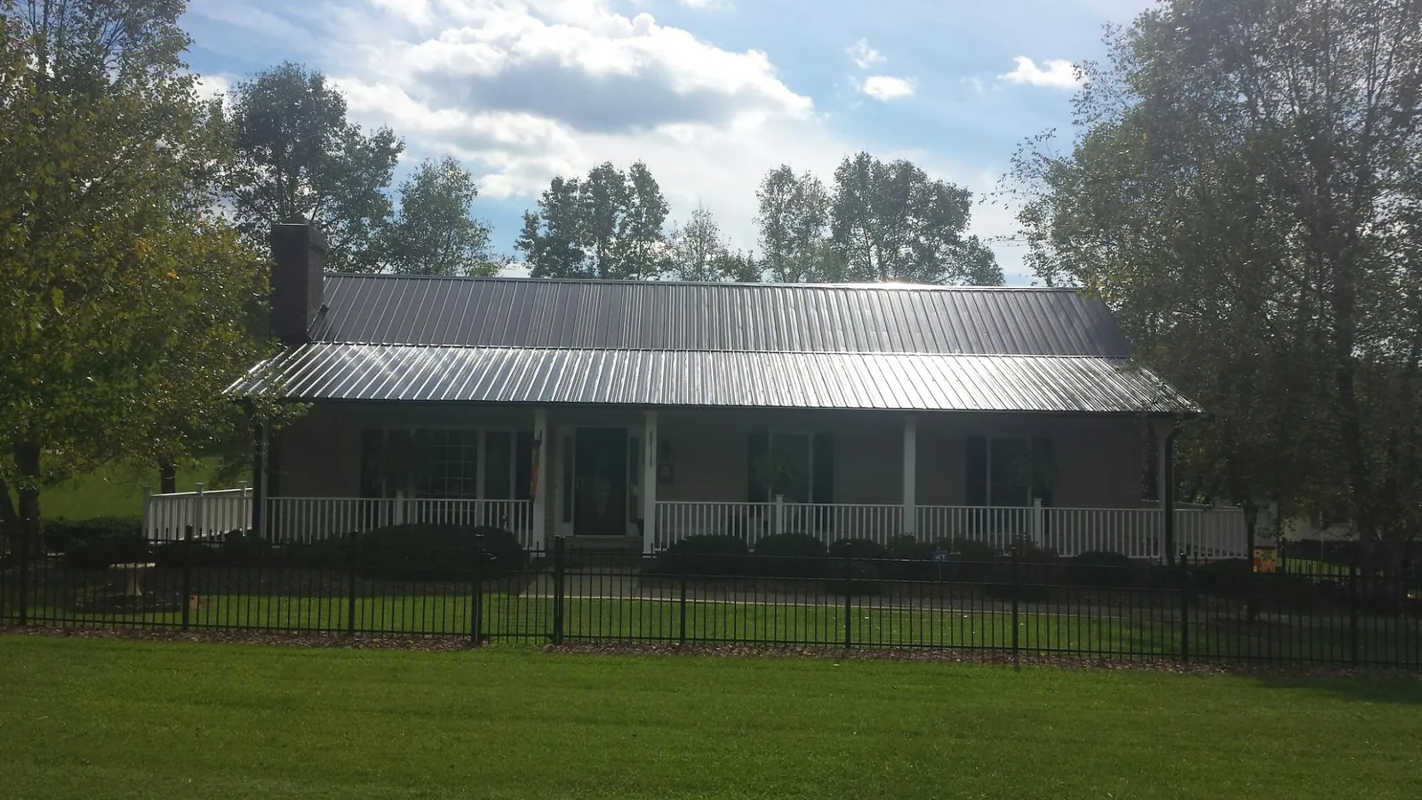 Gray metal roof on a brick ranch with a full width front porch — Gutter Guard Installation work by our crew in Humeston