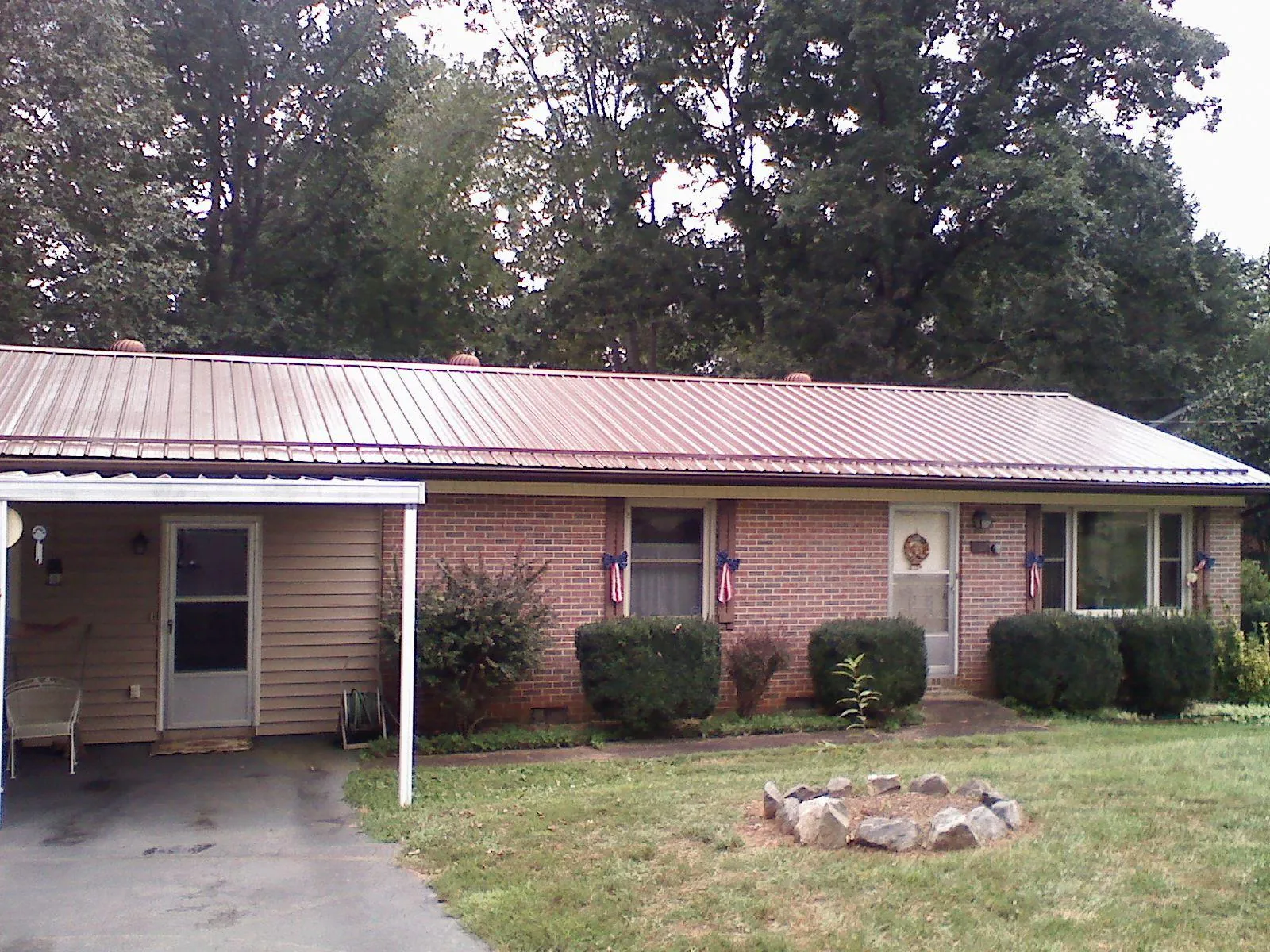 Bronze metal roof and carport on a brick ranch home — Roof Repair work by our crew in Humeston