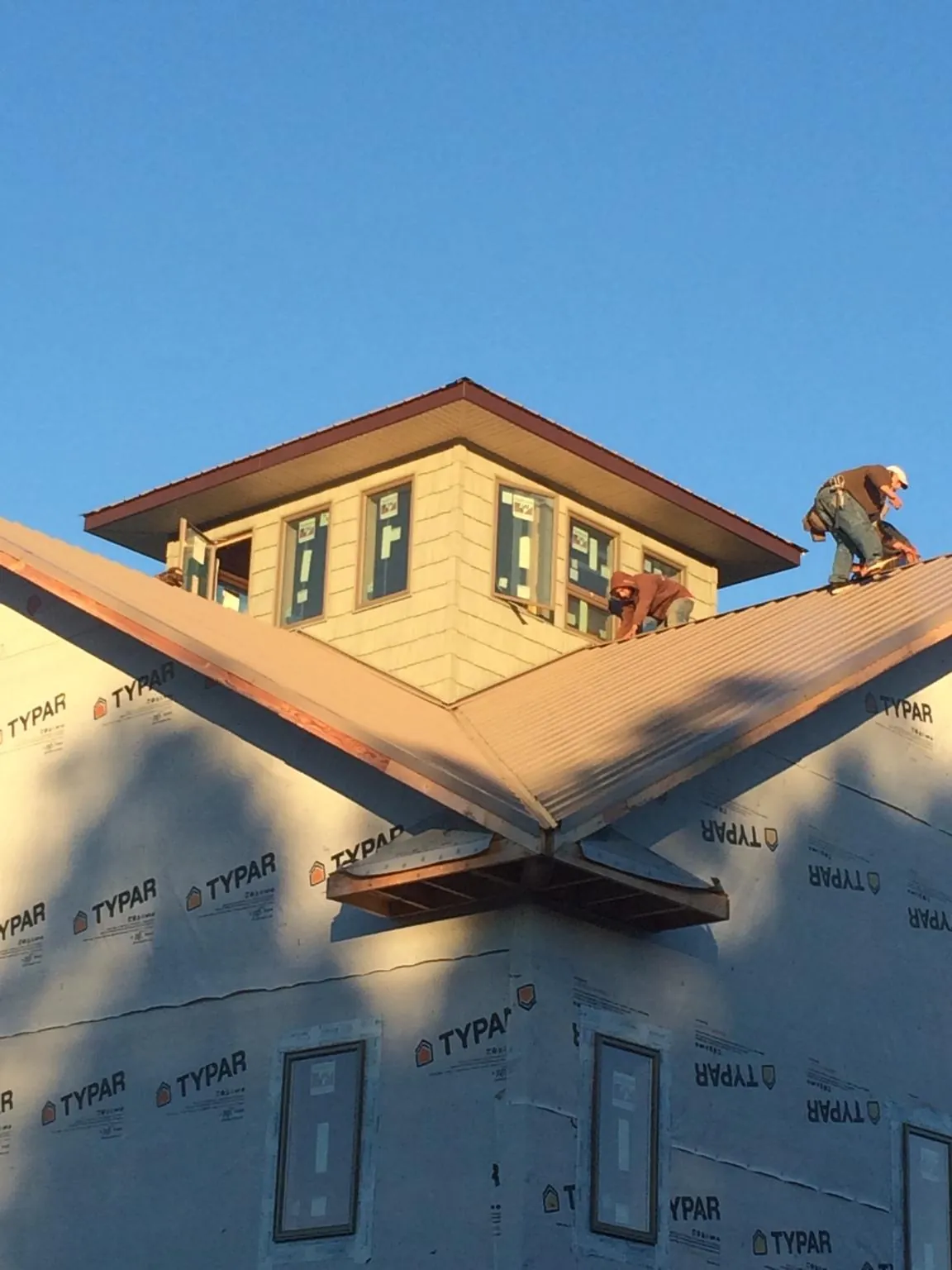Roofers working around a rooftop cupola on a new metal roof at sunset — Roof Waterproofing in Humeston by Roofing Brothers